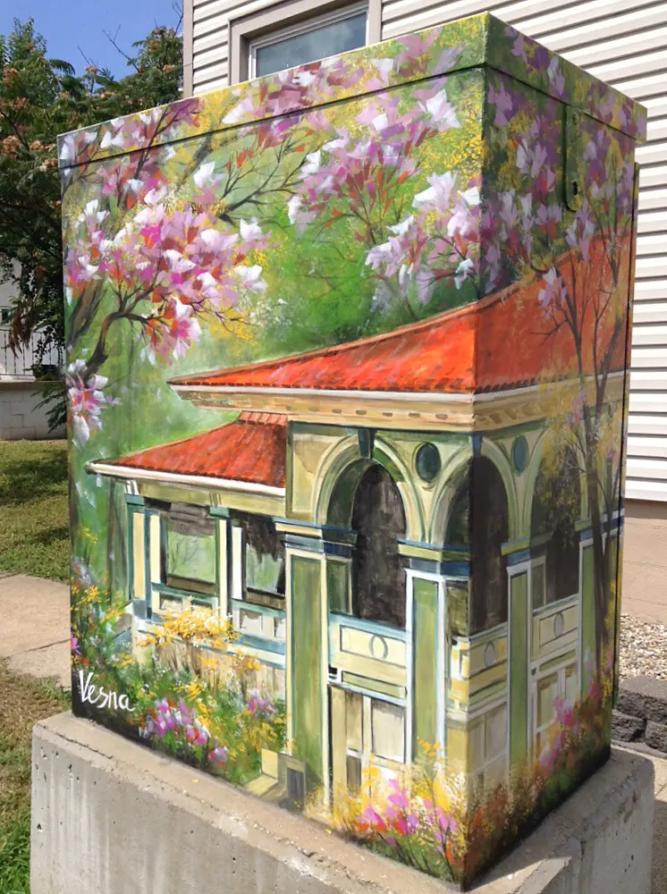 A utility box painted with a Victorian house and blossoms