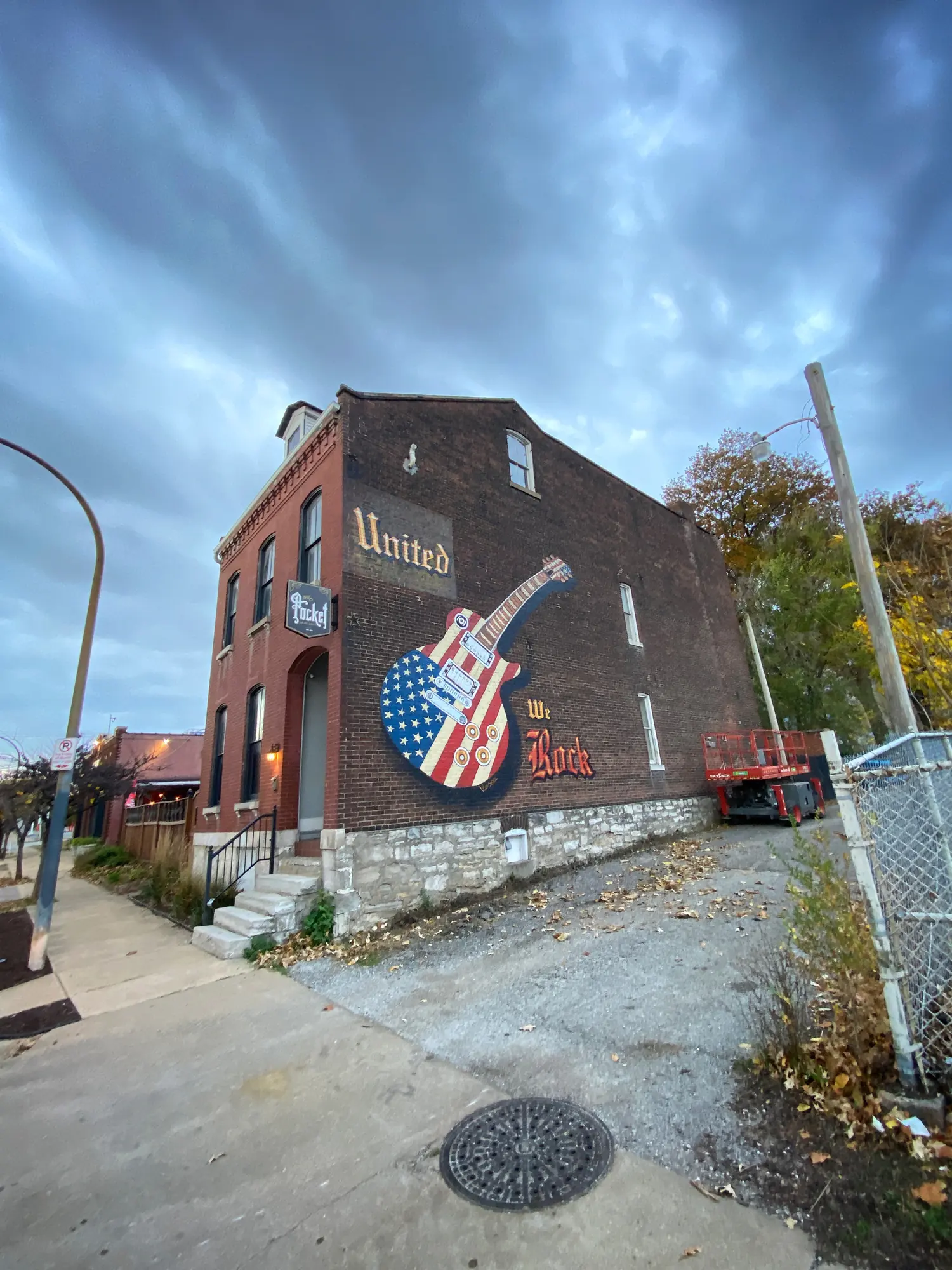 A brick building with a large guitar mural on its side