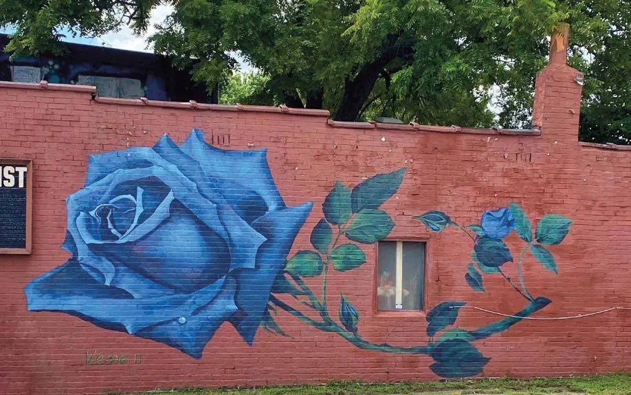 A blue rose mural on a red brick wall