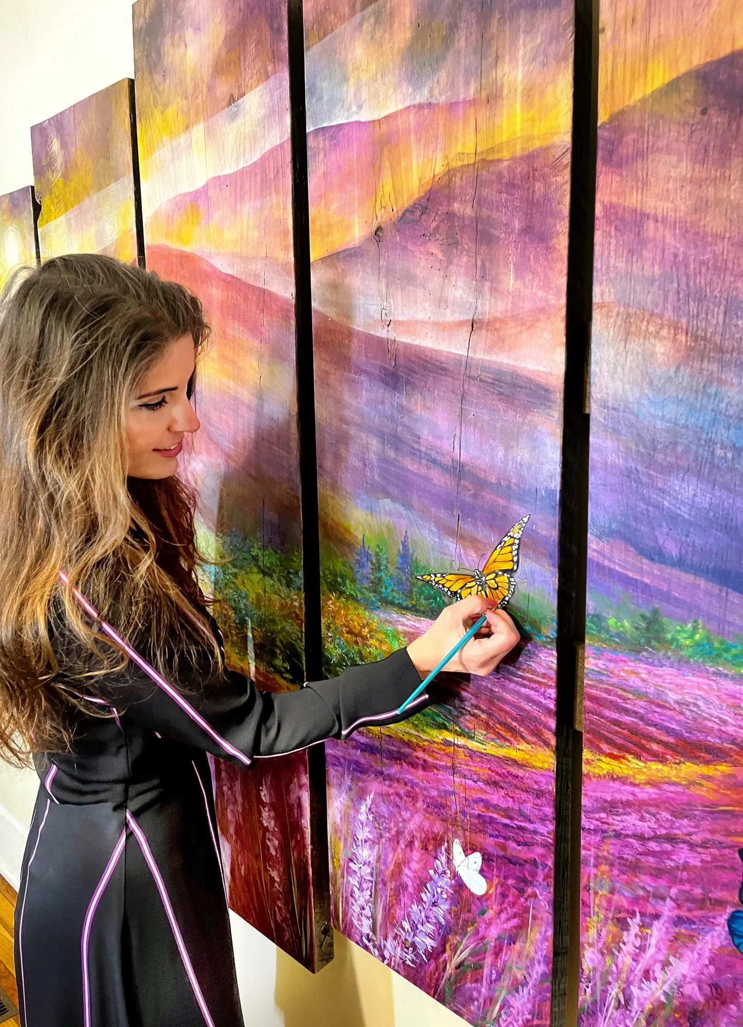 Vesna Delevska beside a multi-panel lavender field painting she created on commission